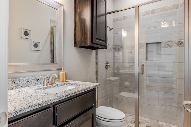 bathroom featuring vanity, toilet, and a shower stall