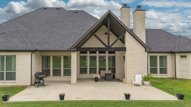 rear view of property with a patio, a chimney, a lawn, brick siding, and roof with shingles