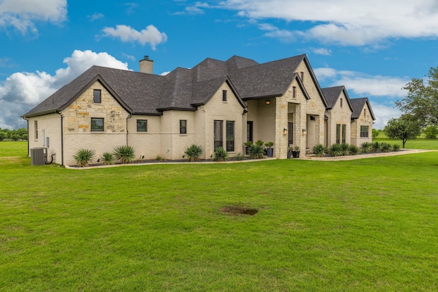 french country inspired facade with a chimney, brick siding, a shingled roof, stone siding, and a front lawn
