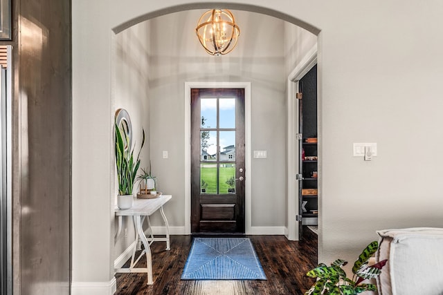 foyer featuring an inviting chandelier, arched walkways, baseboards, and dark wood finished floors