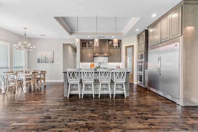 dining area with an inviting chandelier, dark wood-type flooring, baseboards, a raised ceiling, and recessed lighting