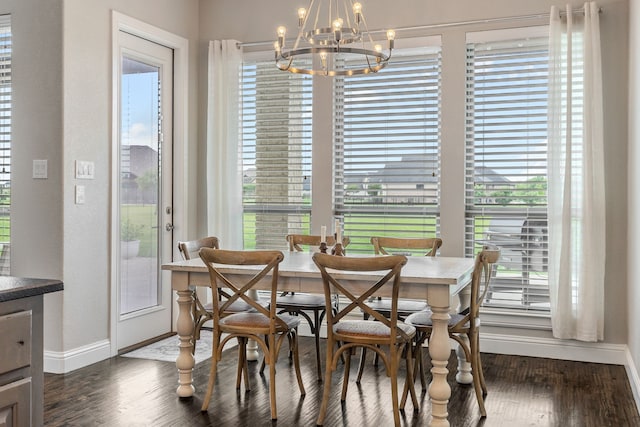 dining area featuring dark wood-style flooring, a wealth of natural light, baseboards, and a notable chandelier