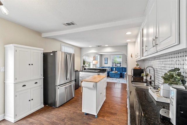 2512 Halloran St, Fort Worth, TX 76107 - kitchen with a sink, freestanding refrigerator, white cabinetry, arched walkways, and dark wood-style floors