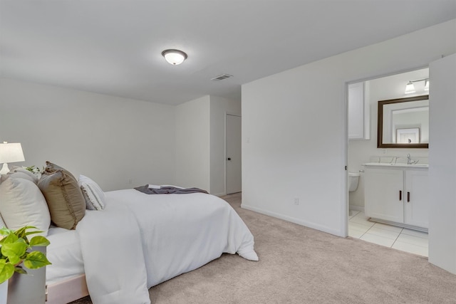 5229 Cockrell Ave, Fort Worth, TX 76133 - bedroom featuring light carpet, light tile patterned floors, baseboards, ensuite bath, and a sink