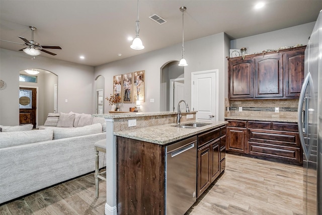 kitchen featuring visible vents, a sink, open floor plan, arched walkways, and appliances with stainless steel finishes