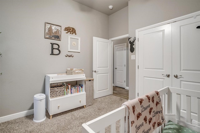 carpeted bedroom featuring baseboards, a closet, and a crib