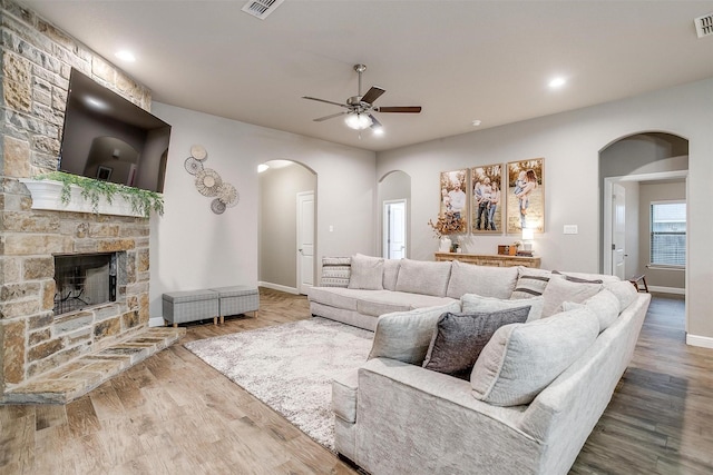 living room with wood finished floors, recessed lighting, a fireplace, ceiling fan, and arched walkways