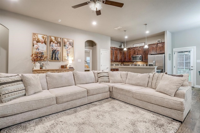 living area featuring a ceiling fan, recessed lighting, visible vents, wood finished floors, and arched walkways