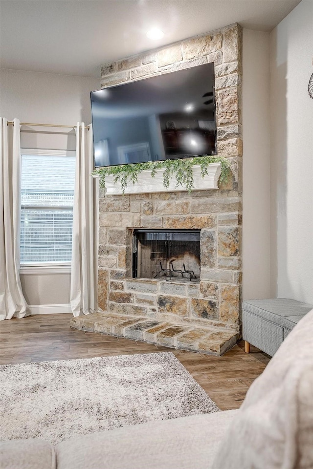 interior details featuring baseboards, a stone fireplace, and wood finished floors
