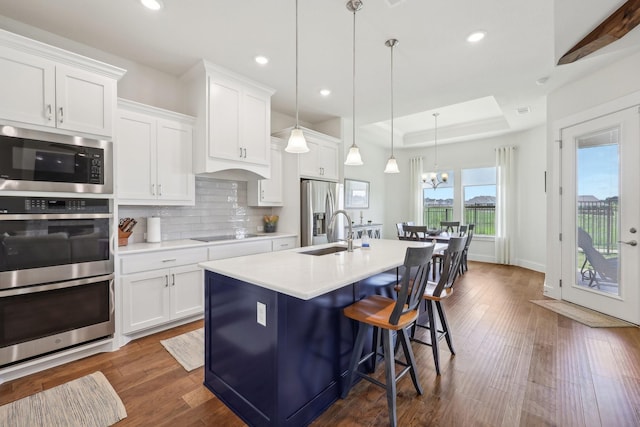 846 Cordoba Ln, Rockwall, TX 75087 - kitchen featuring stainless steel appliances, a sink, a kitchen breakfast bar, a tray ceiling, and light countertops