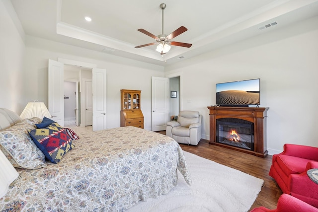 846 Cordoba Ln, Rockwall, TX 75087 - bedroom with a tray ceiling, wood finished floors, baseboards, a glass covered fireplace, and recessed lighting
