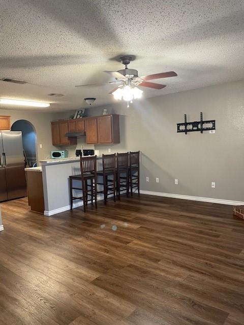 502 Blueberry Hill Ln, Mansfield, TX 76063 - kitchen with stainless steel refrigerator with ice dispenser, a peninsula, ceiling fan, a textured ceiling, and dark wood-style flooring
