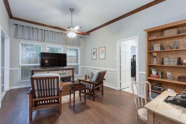 sitting room featuring a ceiling fan, dark wood-style flooring, ornamental molding, and a wainscoted wall