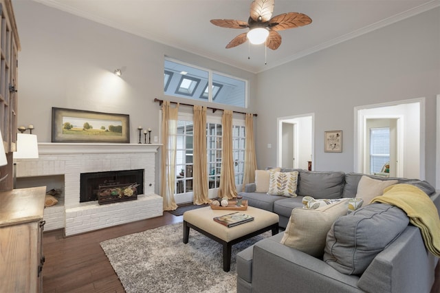 living room featuring a ceiling fan, a healthy amount of sunlight, dark wood finished floors, and crown molding