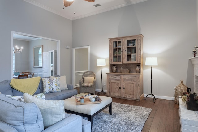 living area with ornamental molding, ceiling fan with notable chandelier, light wood-style flooring, and visible vents