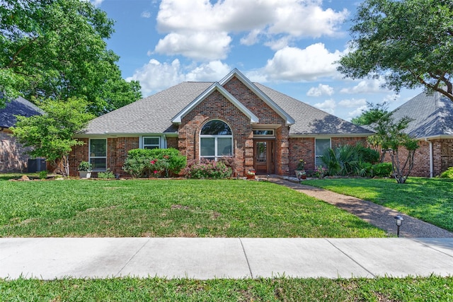 ranch-style house featuring a shingled roof, brick siding, and a front lawn