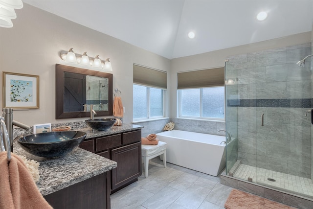 full bathroom featuring double vanity, a sink, a shower stall, vaulted ceiling, and a washtub