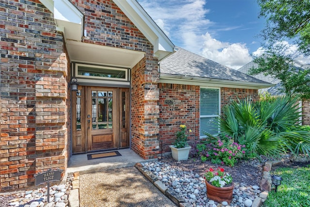property entrance featuring brick siding and roof with shingles