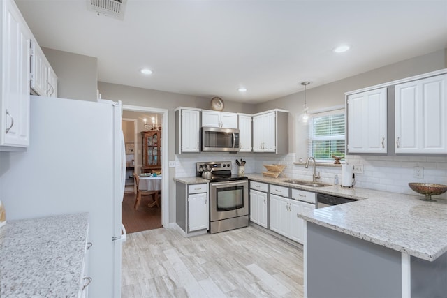 kitchen featuring light wood-style flooring, visible vents, a sink, decorative backsplash, and stainless steel appliances