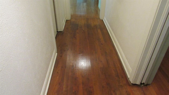 1509 N Gaines St, Ennis, TX 75119 - hall featuring a textured wall, baseboards, and dark wood finished floors