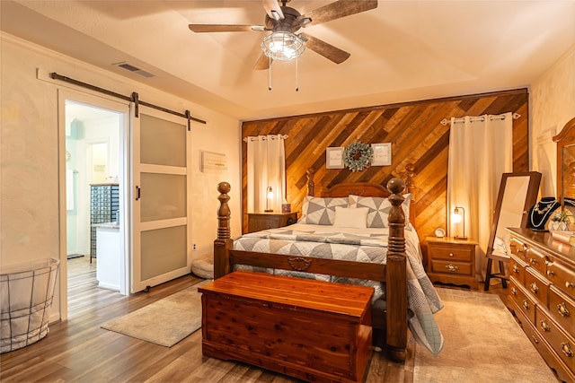 1307 S Westador Dr, Arlington, TX 76015 - bedroom featuring wooden walls, wood finished floors, a barn door, and ceiling fan