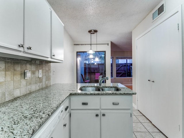 4242 N Capistrano Dr Unit 203, Dallas, TX 75287 - kitchen featuring a sink, a textured ceiling, visible vents, decorative backsplash, and white cabinets