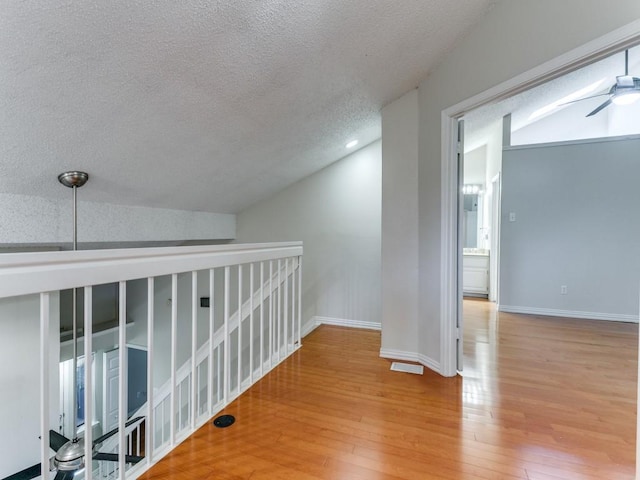 4242 N Capistrano Dr Unit 203, Dallas, TX 75287 - hall with lofted ceiling, a textured ceiling, wood-type flooring, and an upstairs landing