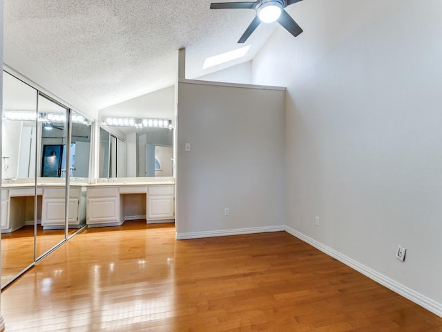 4242 N Capistrano Dr Unit 203, Dallas, TX 75287 - unfurnished bedroom featuring lofted ceiling, a textured ceiling, light wood-style flooring, and built in study area