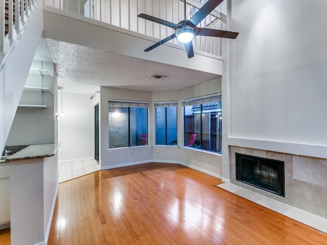 4242 N Capistrano Dr Unit 203, Dallas, TX 75287 - unfurnished living room with hardwood / wood-style flooring, visible vents, a fireplace, a ceiling fan, and baseboards