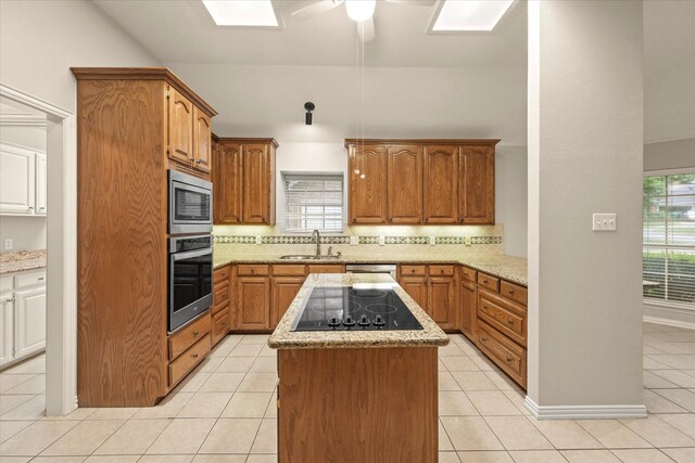 kitchen with appliances with stainless steel finishes, tasteful backsplash, a kitchen island, light stone counters, and healthy amount of natural light
