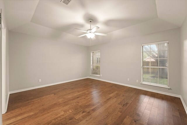 empty room featuring healthy amount of natural light, dark wood-type flooring, baseboards, and a ceiling fan