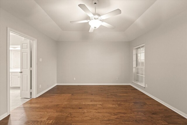 unfurnished room featuring dark wood finished floors, a ceiling fan, and baseboards