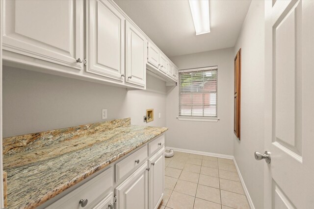 laundry room featuring cabinet space, baseboards, washer hookup, and light tile patterned flooring