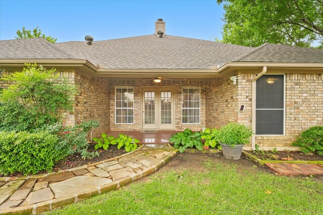 property entrance with brick siding, roof with shingles, a chimney, and covered porch