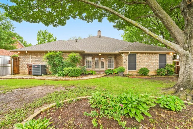 view of front of house with central AC unit, a chimney, brick siding, a shingled roof, and a gate