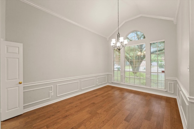 unfurnished dining area featuring a chandelier, lofted ceiling, wainscoting, wood finished floors, and crown molding