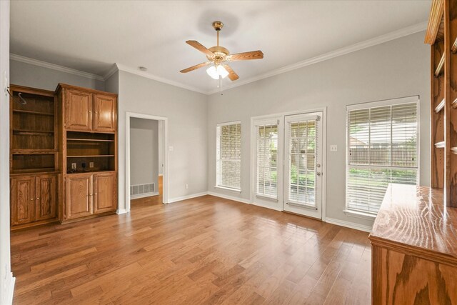 unfurnished living room with ceiling fan, light wood finished floors, baseboards, and crown molding