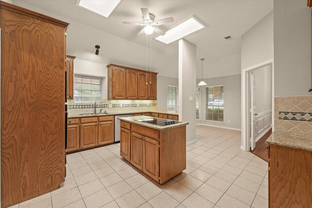 kitchen featuring a sink, light tile patterned floors, a skylight, and ceiling fan