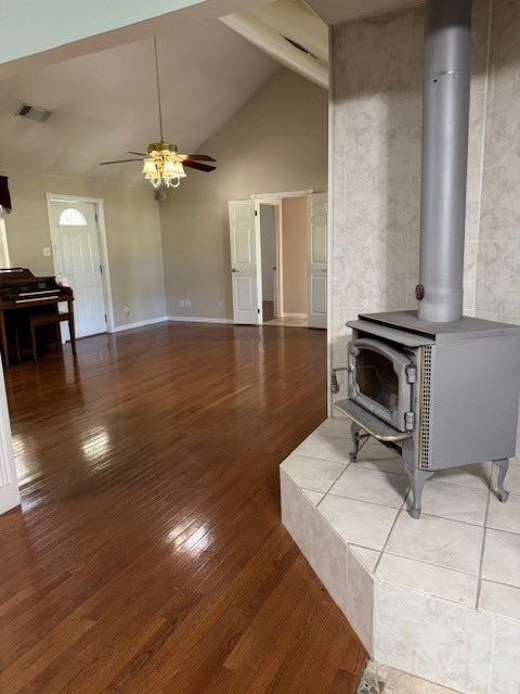 7249 Peden Rd, Azle, TX 76020 - unfurnished living room with wood finished floors, high vaulted ceiling, visible vents, ceiling fan, and a wood stove