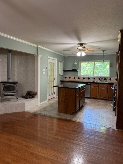 7249 Peden Rd, Azle, TX 76020 - kitchen featuring a ceiling fan, a center island, dark countertops, light wood-type flooring, and a wood stove