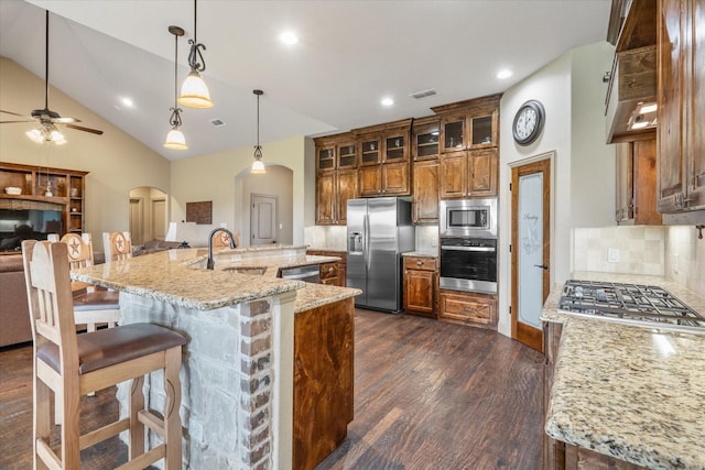 360 Rs County Road 3419, Emory, TX 75440 - kitchen with stainless steel appliances, a sink, arched walkways, brown cabinetry, and dark wood-style floors