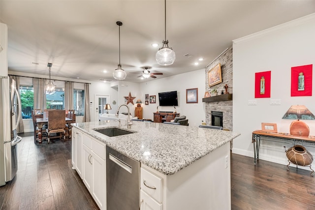 kitchen with stainless steel appliances, a sink, dark wood-style floors, white cabinets, and light stone countertops