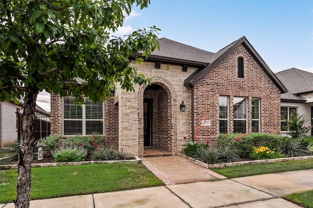 view of front of property featuring brick siding, roof with shingles, and stone siding