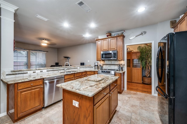 kitchen with a sink, a peninsula, stainless steel appliances, visible vents, and a kitchen island