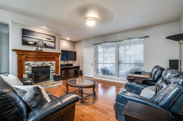 living area with a stone fireplace and wood finished floors