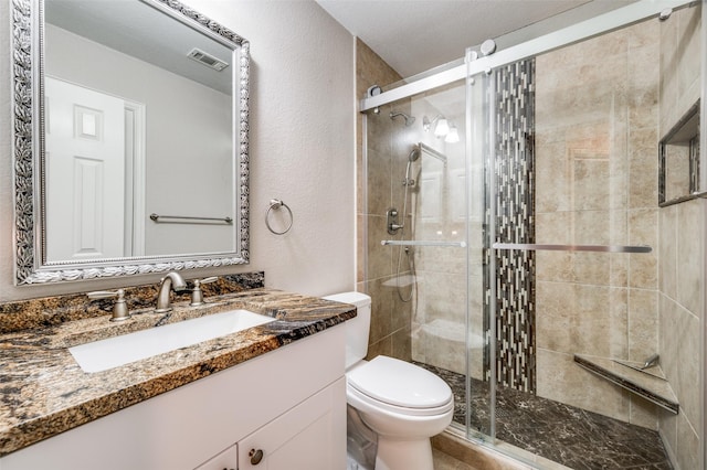 full bathroom featuring toilet, vanity, visible vents, and a shower stall