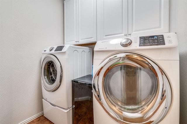 clothes washing area featuring washing machine and dryer and cabinet space