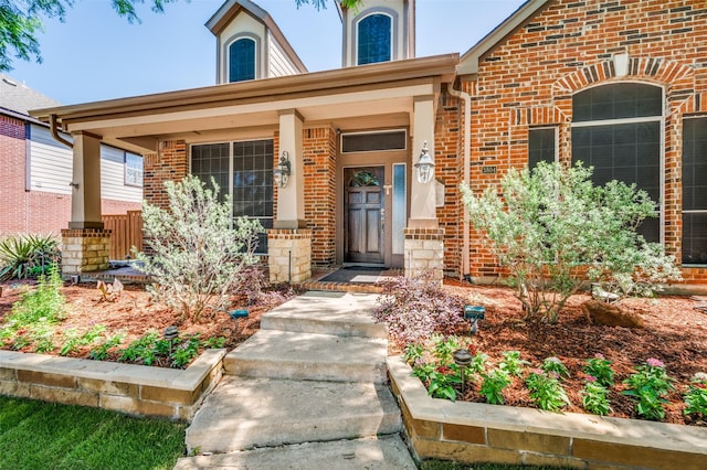 property entrance featuring covered porch and brick siding