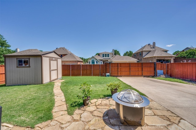 view of yard with an outdoor fire pit, a patio, a fenced backyard, and a storage unit