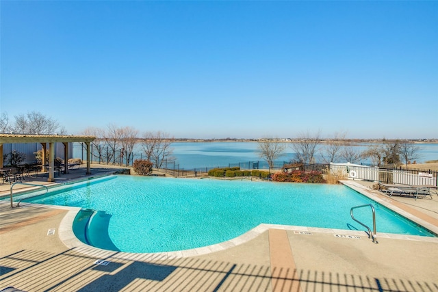 community pool featuring a water view, fence, and a patio